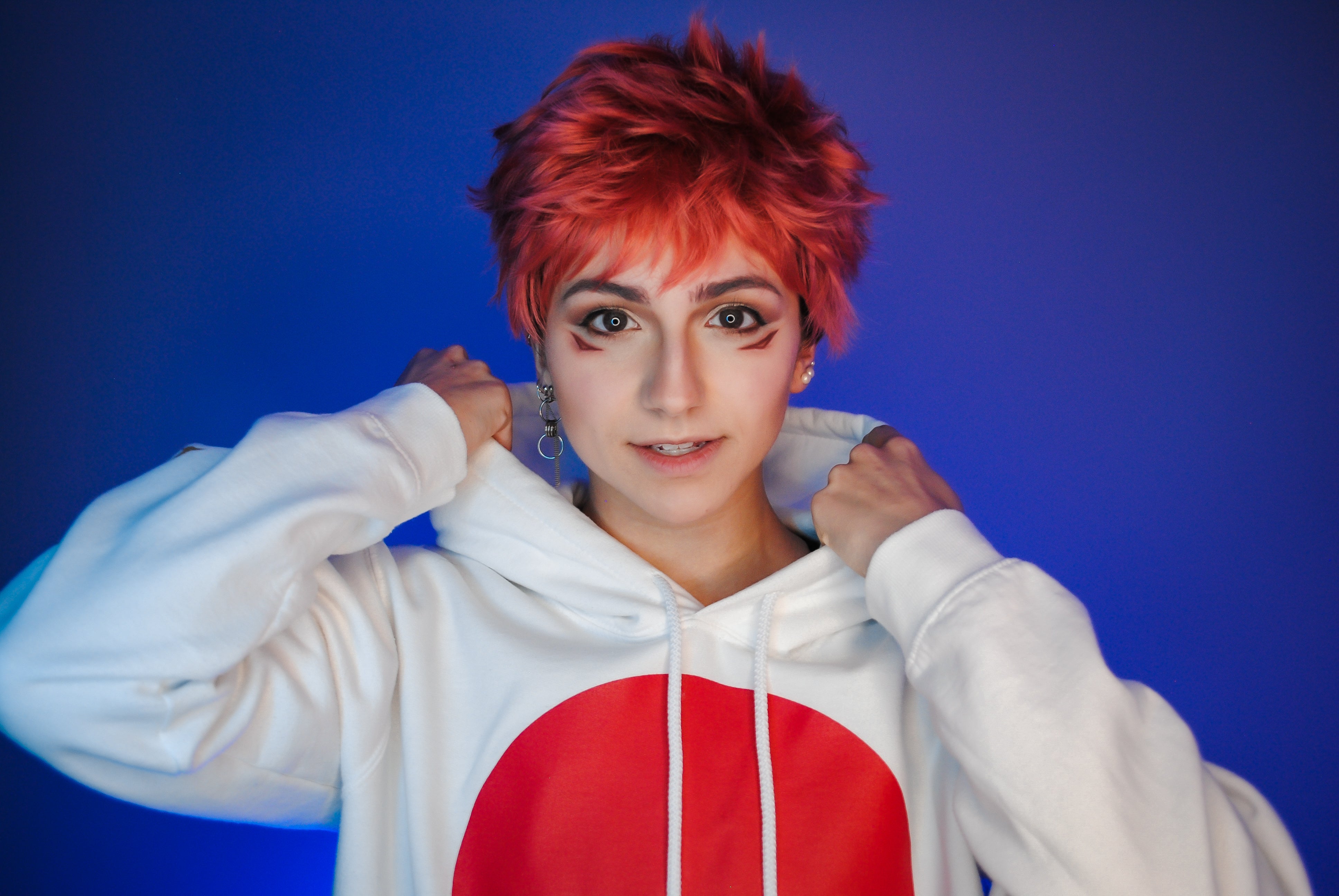 Person wearing a white hoodie with a red circle design against a blue background