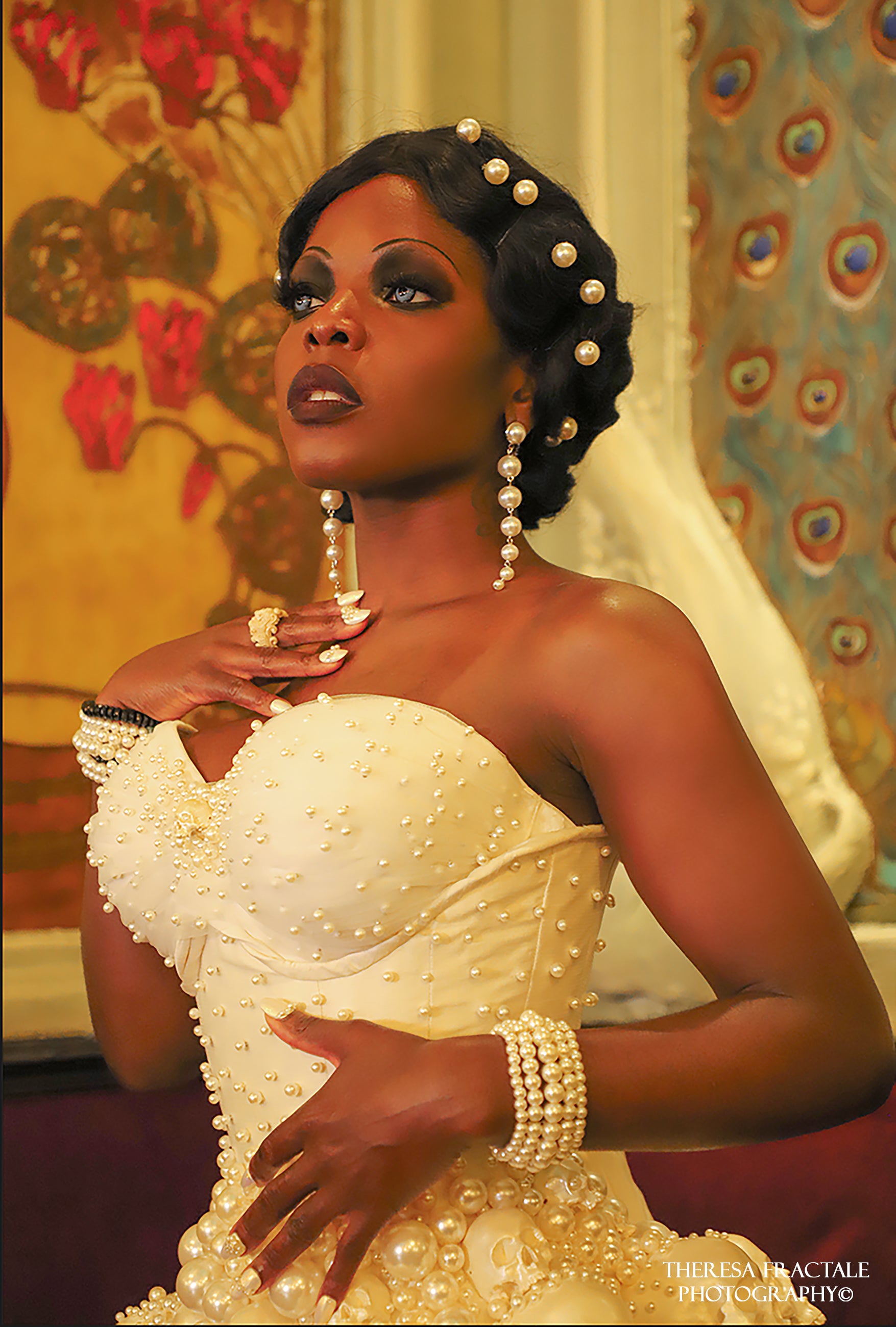 Woman in a white beaded dress with jewelry against a decorative wall.