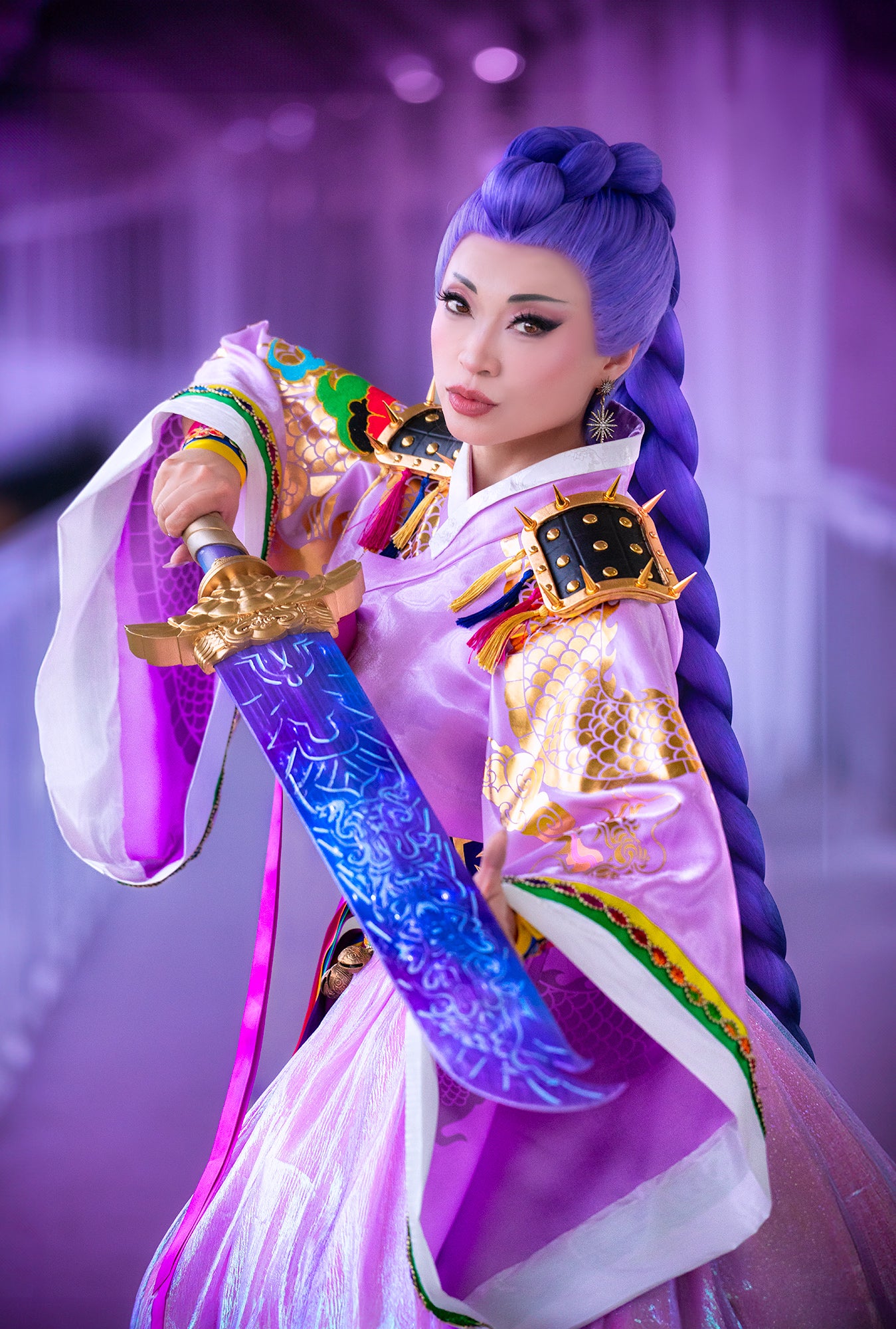 Person in elaborate traditional costume with a sword, set against a blurred background