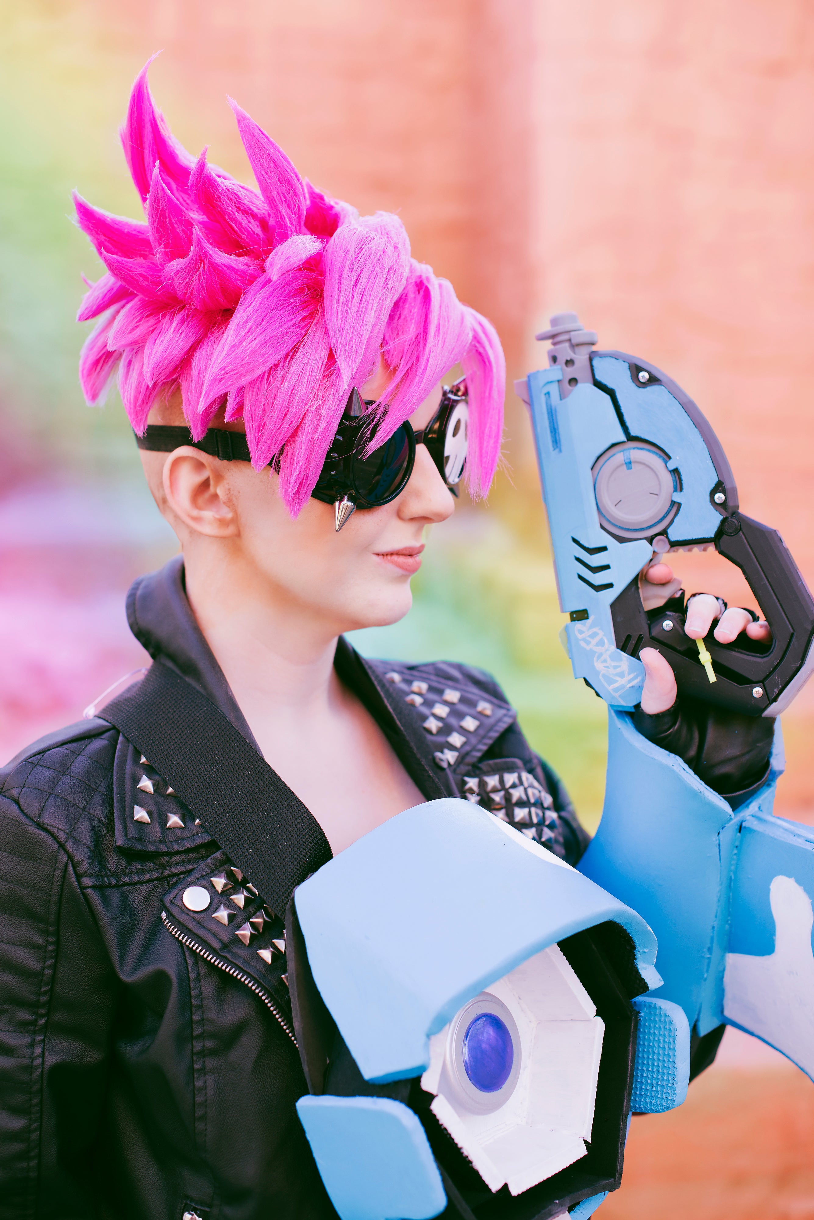 Person with pink hair and futuristic gloves against a blurred background